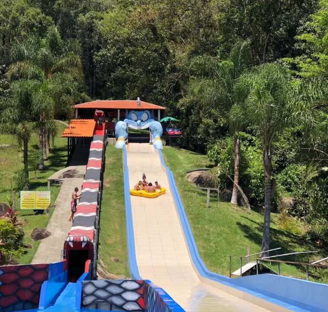 Pessoas em uma boia amarela descendo a rampa da atração Tapete Mágico